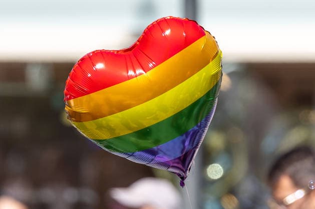 CSD Nürnberg 2026 Nürnberg Pride Week, Nürnberg, 08.08.2026 Ein herzförmiger Luftballon in Regenbogenfarben schwebt über der Parade des Christopher Street Day durch die Innenstadt. Im unscharfen Hintergrund sind Teilnehmer der Parade zu erkennen. Nürnberg Bayern Deutschland