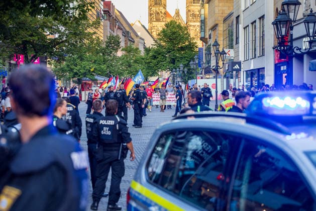Polizeieinsatz bei Montagsdemo von Team Menschenrechte und Gegenprotesten, Nürnberg, 10.087.2026 Polizeikräfte begleiten einen Demonstrationszug von Team Menschenrechte durch die Karolinenstraße. Ein Einsatzfahrzeug mit Blaulicht steht am Rand der Fußgängerzone, im Hintergrund sind Fahnen und Teilnehmer des Aufzugs zu erkennen. Nürnberg Bayern Deutschland