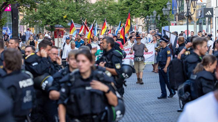 Polizeieinsatz bei Montagsdemo von Team Menschenrechte und Gegenprotesten, Nürnberg, 10.087.2026 Polizeikräfte begleiten einen Demonstrationszug der Team Menschenrechte durch die Karolinenstraße. Teilnehmer tragen Deutschlandfahnen und Transparente, während zahlreiche Einsatzkräfte den Aufzug sichern. Nürnberg Bayern Deutschland