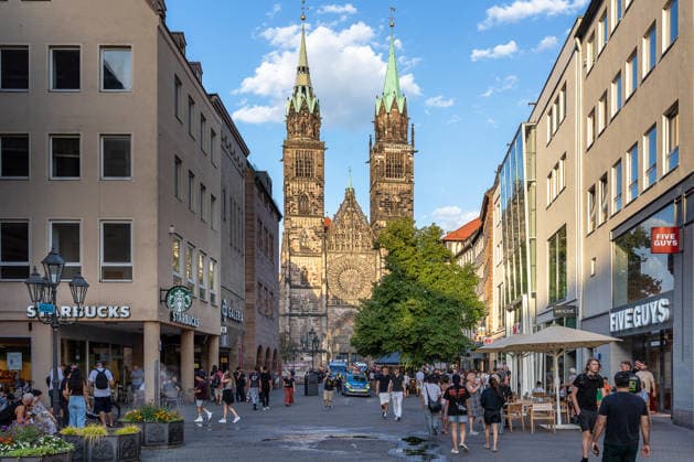 Polizeieinsatz bei Montagsdemo von Team Menschenrechte und Gegenprotesten, Nürnberg, 10.087.2026 Demonstrationszug von Team Menschenrechte durch die Karolinenstraße in der Fußgängerzone. Passanten und CafÃ besucher beobachten den Aufzug vor der Kulisse der Lorenzkirche. Nürnberg Bayern Deutschland