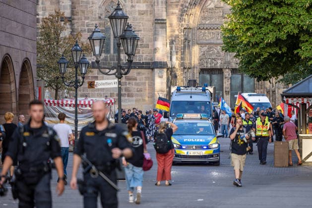 Polizeieinsatz bei Montagsdemo von Team Menschenrechte und Gegenprotesten, Nürnberg, 10.087.2026 Polizeikräfte begleiten einen Demonstrationszug von Team Menschenrechte und Gegenprotesten in der Karolinenstraße. Ein Einsatzfahrzeug der Polizei mit Blaulicht fährt inmitten von Demonstranten mit Deutschlandfahnen durch die Fußgängerzone. Nürnberg Bayern Deutschland