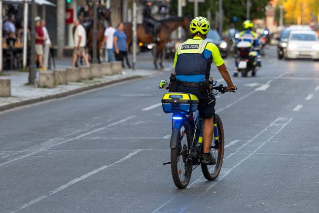 Polizeieinsatz bei Montagsdemo von Team Menschenrechte und Gegenprotesten, Nürnberg, 10.087.2026 Ein Polizeibeamter auf einem Fahrrad begleitet einen Einsatz im Straßenverkehr, im Hintergrund sind berittene Polizei und ein Polizeimotorrad zu erkennen. Nürnberg Bayern Deutschland
