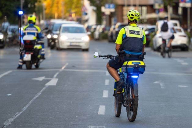 Polizeieinsatz bei Montagsdemo von Team Menschenrechte und Gegenprotesten, Nürnberg, 10.087.2026 Polizeibeamte auf Fahrrädern und Motorrad begleiten den Straßenverkehr während eines Einsatzes. Ein Fahrradstreife mit Blaulicht fährt im Verkehr mit, im Hintergrund folgt ein weiterer Beamter auf einem Polizeimotorrad. Nürnberg Bayern Deutschland