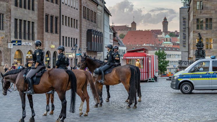 Polizeieinsatz bei Montagsdemo von Team Menschenrechte und Gegenprotesten, Nürnberg, 10.087.2026 Berittene Polizeieinheiten sichern auf dem Lorenzerplatz das Geschehen ab. Im Hintergrund sind die Nürnberger Burg sowie historische Gebäude und ein Einsatzfahrzeug der Polizei zu sehen. Nürnberg Bayern Deutschland
