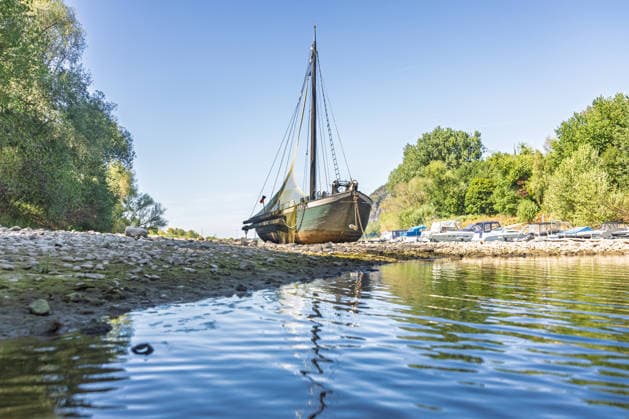 Niedrigwasser am Rhein: Aalschokker Aranka im trockengefallenen Nebenarm bei Insel Grafenwerth - 11.08.26. Niedrigwasser am Rhein: Bei einem Pegelstand von -3 cm am Pegel Oberwinter und 70 cm am Pegel Bonn neue Tiefstwerte liegt der Nebenarm an der Nordspitze der Insel Grafenwerth in Bad Honnef weitgehend trocken. Der historische Aalschokker Aranka liegt auf dem Trockenen, im Hintergrund die Grafenwerther Brücke und der Drachenfels. Die Rheinschifffahrt ist weiterhin stark eingeschränkt. Bad Honnef Insel Grafenwerth Nordrhein-Westfalen Deutschland Copyright: xMarcxJohnx