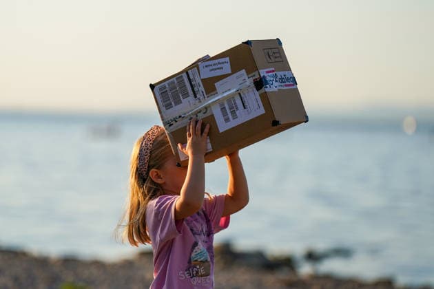 Altenrhein, Bodensee, Schweiz: Mädchen beobachtet eine Sonnenfinsternis mit einer selbstgebauten Lochkamera aus einem Karton. Das Kind richtet die improvisierte Projektionshilfe zur Sonne, im Hintergrund der Bodensee. Sonnenfinsternis, partielle Sonnenfinsternis, Sofi, Astronomie, Sonne, Lochkamera, Projektionsmethode, Augenschutz, Kind, Mädchen, Experiment, Naturphänomen, Wissenschaft, Altenrhein, Bodensee, St. Gallen, Schweiz. Copyright: xJOERANxSTEINSIEKx