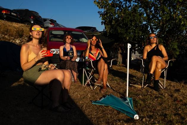 August 12, 2026, Paredes De Coura, Braga, Portugal: A group of festivalgoers wearing certified eclipse glasses sit on the festival grounds and watch the partial solar eclipse during the opening day of Vodafone Paredes de Coura. Paredes De Coura Portugal  - ZUMAs197 20260812_aaa_s197_595 Copyright: xDiogoxBaptistax