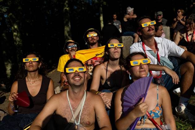 August 12, 2026, Paredes De Coura, Braga, Portugal: Festivalgoers wearing certified eclipse glasses sit on the hillside while watching the partial solar eclipse during the opening day of Vodafone Paredes de Coura. Paredes De Coura Portugal - ZUMAs197 20260812_aaa_s197_591 Copyright: xDiogoxBaptistax