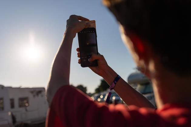August 12, 2026, Paredes De Coura, Braga, Portugal: A festivalgoer uses a phone with a protective filter to watch the partial solar eclipse from the festival grounds during the opening day of Vodafone Paredes de Coura. Paredes De Coura Portugal - ZUMAs197 20260812_aaa_s197_594 Copyright: xDiogoxBaptistax
