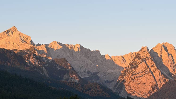 Wetterfeature, Morgenstille am Eibsee: Unterhalb der Zugspitze liegt der See bei Grainau nahe Garmisch-Partenkirchen in den frühen Stunden noch ruhig und nahezu unberührt. Doch an heißen Sommertagen ändert sich das Bild häufig schon ab Mittag. Dann strömen zahlreiche Ausflügler und Urlauber an den durch soziale Medien weltweit bekannt gewordenen Bergsee. Der zunehmende Massentourismus sorgt regelmäßig für einen regelrechten Besucheransturm. Unter dem hohen Verkehrsaufkommen, zugeparkten Straßen und dem großen Andrang leiden zunehmend auch die Anwohner in Grainau und rund um den Eibsee. Grainau Bayern Deutschland Grainau