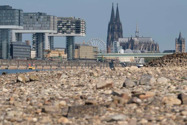 News Bilder des Tages Eine Teleaufnahme zeigt die markante Kölner Stadtkulisse mit den modernen Kranhäusern im Rheinauhafen und den gotischen Türmen des Kölner Doms im Hintergrund. Im unscharfen Vordergrund erstreckt sich das weitläufige, freigelegte Kiesel- und Steinufer des Rheins, das die Auswirkungen von extremem sommerlichem Niedrigwasser dokumentiert.