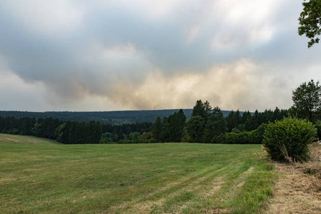 Waldbrand im Hohen Venn Blick von der deutsch-belgischen Grenze bei Kalterherberg - 15.08.26 Blick von der Gemeinde Monschau auf den Großbrand im Hohen Venn nahe der deutsch-belgischen Grenze. Im Hintergrund Rauchsäulen des Feuers. Insgesamt zwei Löschhubschrauber sind im Einsatz und werfen jeweils rund 3.000 Liter Wasser ab. Der Hochmoorbrand hat bereits rund 2.000 Hektar Wald- und Moorgebiet erfasst, die tiefen Torfschichten begünstigen einen langanhaltenden Schwelbrand. Auf belgischer Seite laufen bereits Evakuierungen, für Teile Monschaus wird eine mögliche Räumung vorbereitet. Monschau Kalterherberg Nordrhein-Westfalen Deutschland Copyright: xMarcxJohnx