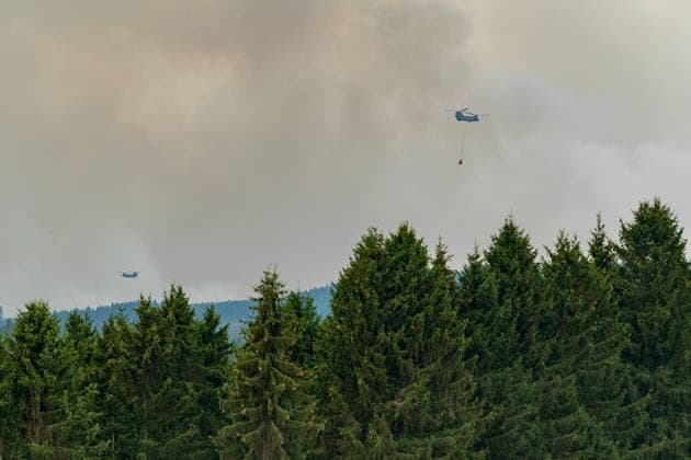 Waldbrand im Hohen Venn Blick von der deutsch-belgischen Grenze bei Kalterherberg - 15.08.26 Blick von Kalterherberg (Gemeinde Monschau) auf den Großbrand im Hohen Venn nahe der deutsch-belgischen Grenze.Im Hintergrund Rauchsäulen des Feuers und ein Löschhubschrauber mit Wasserbehälter im Anflug. Insgesamt zwei Löschhubschrauber sind im Einsatz und werfen jeweils rund 3.000 Liter Wasser ab. Der Hochmoorbrand hat bereits rund 2.000 Hektar Wald- und Moorgebiet erfasst, die tiefen Torfschichten begünstigen einen langanhaltenden Schwelbrand. Auf belgischer Seite laufen bereits Evakuierungen, für Teile Monschaus wird eine mögliche Räumung vorbereitet. Monschau Kalterherberg Nordrhein-Westfalen Deutschland Copyright: xMarcxJohnx