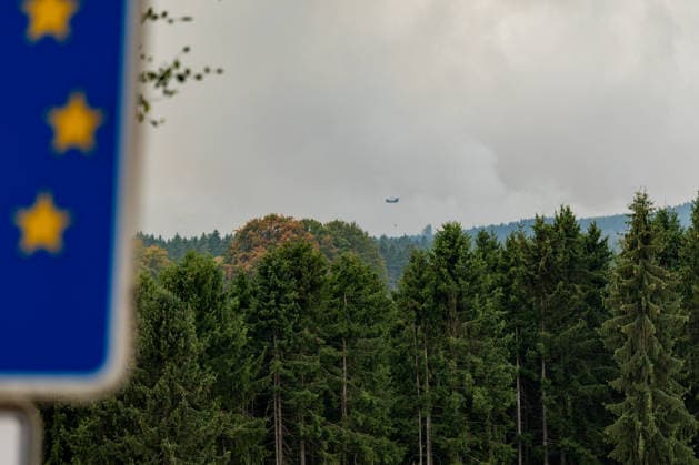 Waldbrand im Hohen Venn Blick von der deutsch-belgischen Grenze bei Kalterherberg - 15.08.26 Blick von Kalterherberg (Gemeinde Monschau) auf den Großbrand im Hohen Venn nahe der deutsch-belgischen Grenze. Im Vordergrund ein blaues Grenzschild, im Hintergrund Rauchsäulen des Feuers und ein Löschhubschrauber mit Wasserbehälter im Anflug. Insgesamt zwei Löschhubschrauber sind im Einsatz und werfen jeweils rund 3.000 Liter Wasser ab. Der Hochmoorbrand hat bereits rund 2.000 Hektar Wald- und Moorgebiet erfasst, die tiefen Torfschichten begünstigen einen langanhaltenden Schwelbrand. Auf belgischer Seite laufen bereits Evakuierungen, für Teile Monschaus wird eine mögliche Räumung vorbereitet. Monschau Kalterherberg Nordrhein-Westfalen Copyright: xMarcxJohnx