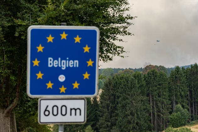 Waldbrand im Hohen Venn Blick von der deutsch-belgischen Grenze bei Kalterherberg - 16.08.26 Blick von Kalterherberg (Gemeinde Monschau) auf den Großbrand im Hohen Venn nahe der deutsch-belgischen Grenze. Im Vordergrund ein blaues Grenzschild, im Hintergrund Rauchsäulen des Feuers. Insgesamt zwei Löschhubschrauber sind im Einsatz und werfen jeweils rund 3.000 Liter Wasser ab. Der Hochmoorbrand hat bereits rund 2.000 Hektar Wald- und Moorgebiet erfasst, die tiefen Torfschichten begünstigen einen langanhaltenden Schwelbrand. Auf belgischer Seite laufen bereits Evakuierungen, für Teile Monschaus wird eine mögliche Räumung vorbereitet. Monschau Kalterherberg Nordrhein-Westfalen Deutschland Copyright: xMarcxJohnx