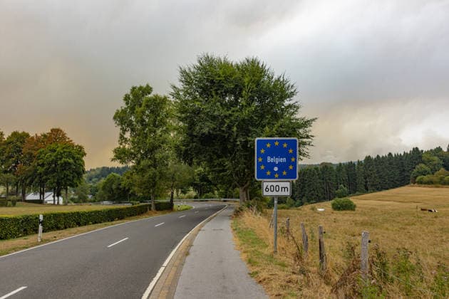 Waldbrand im Hohen Venn Blick von der deutsch-belgischen Grenze bei Kalterherberg - 16.08.26 Blick von Kalterherberg (Gemeinde Monschau) auf den Großbrand im Hohen Venn nahe der deutsch-belgischen Grenze. Im Vordergrund ein blaues Grenzschild, im Hintergrund Rauchsäulen des Feuers. Insgesamt zwei Löschhubschrauber sind im Einsatz und werfen jeweils rund 3.000 Liter Wasser ab. Der Hochmoorbrand hat bereits rund 2.000 Hektar Wald- und Moorgebiet erfasst, die tiefen Torfschichten begünstigen einen langanhaltenden Schwelbrand. Auf belgischer Seite laufen bereits Evakuierungen, für Teile Monschaus wird eine mögliche Räumung vorbereitet. Monschau Kalterherberg Nordrhein-Westfalen Deutschland Copyright: xMarcxJohnx