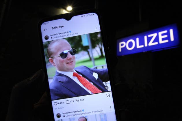 Ein Mann hält vor einem Polizeikommissariat ein Smartphone in der Hand, auf dem der Instagram-Account von Windkraftbetrüger Hendrik Holt geöffnet wurde. Er ist nach einem genehmigten Ausgang nicht in die Justizvollzugsanstalt in Berlin zurückgekehrt und hat sich offenbar nach Russland abgesetzt hat. Jedenfalls postete er auf seinem Instagram-Account unter anderem ein Video mit dem Titel: Liebesgrüße aus Moskau . Die Sicherheitsbehörden fahnden nach Holt. Symbolbild Symbolfoto. Winterhude Hamburg