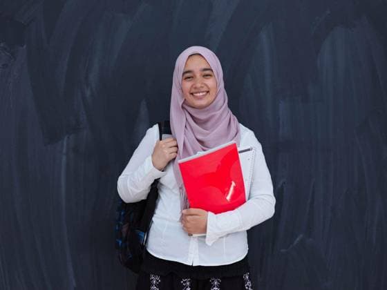 portrait of happy female middle eastern university student against black chalkboard in classroom model released Symbolfoto Copyright: xdotshockx Panthermedia81322590.jpg