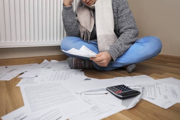Ein Mann mit Schal sitzt mit Rechnungen und einem Taschenrechner neben dem Heizkörper auf dem Boden und macht sich Sorgen wegen der hohen Heizkosten A man wearing a scarf sits on the floor with bills and a calculator next to the radiator and is worried about the high heating costs Copyright: imageBROKER KyryloxSyvun ibxiqx18688159.jpg ,model released, Symbolfoto ,property released