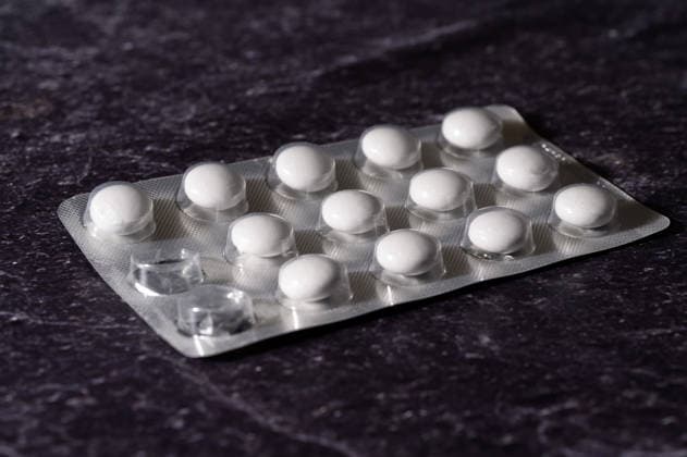 Blisterpackung mit weißen Tabletten diagonal auf Schiefer , Waldsee, Deutschland 16.09.2026: Eine angebrochene Blisterpackung mit weißen runden Tabletten liegt diagonal auf einer dunklen Schieferplatte. Symbolbild für Arzneimittel und Apothekenpreise.