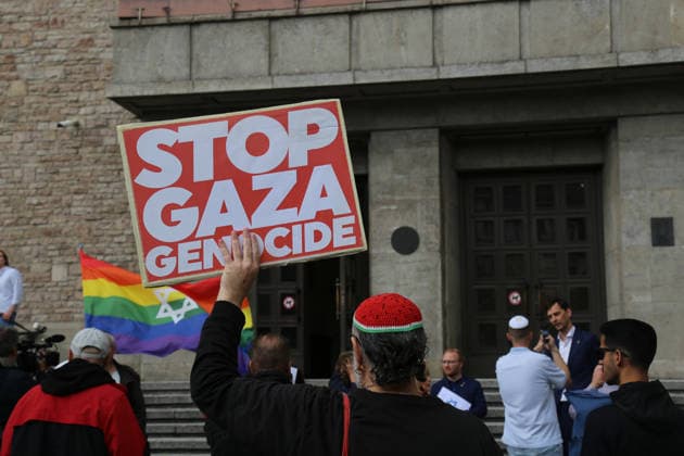 Berlin, Deutschland 17.09.2026: Ein Mann hält vor dem Rathaus Neukölln während der Solidaritätsaktion Berlin trägt Davidstern ein Plakat mit der Aufschrift STOP GAZA GENOCIDE. Im Hintergrund Teilnehmer der Aktion sowie eine Regenbogenflagge mit Davidstern. Gaza, Israel, Nahostkonflikt, Protest, Gegenprotest, Davidstern, Solidarität, Antisemitismus, Rathaus Neukölln. Copyright: xAlonxDavidx