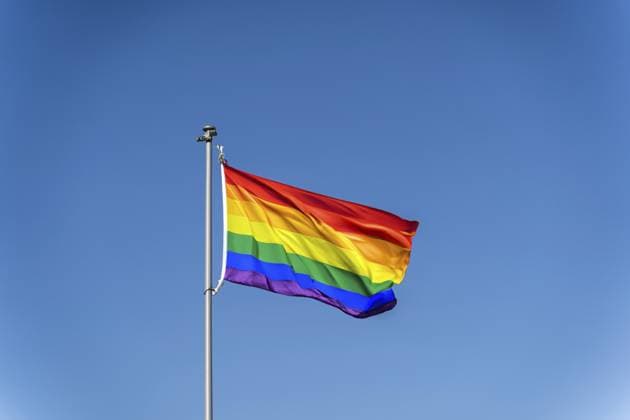 Die Regenbogenflagge der LGBTQ Community weht vor dem Hintergrund eines blauen, klaren Himmels. Eine Regenbogenflagge weht vor einem klaren blauen Himmel und symbolisiert den LGBTQ Stolz The rainbow flag of the LGBTQ community flies against the backdrop of a blue clear sky, A rainbow flag waving against a clear blue sky symbolizing LGBTQ pride Copyright: imageBROKER TatsianaxKalasouskay ibxmdz18819089.jpg