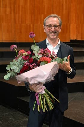 Pressekonferenz zur Vorstellung des designierten Intendanten der Salzburger Festpiele im Grossen festspielhaus in Salzburg, fotografiert am 18.09.26. Das Bild zeigt den designierten Intendanten (ab 1.1.2027) der Salzburger Festspiele, den Belgier Peter de Caluwe mit Blumenstrauß 2026 - Pressekonferenz zur Vorstellung des designierten Intendanten der Salzburger Festpiele im Grossen festspielhaus in Salzburg, am 18.09.26