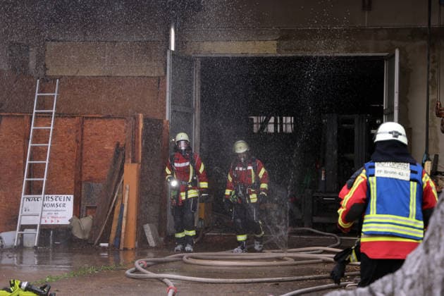 zwei Feuerwehrleute laufen aus dem Gebäude, Feuer im ehemaliges Werkstattgebäude Naturstein Stefan Wormser, Pestalozzistraße Friedhofsweg, 20.09.2026, Oberfranken, Bayern,