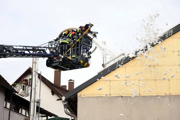 zwei Feuerwehrleute in der Drehleiter spritzen Schaum in das Gebäude dahinter der Korb einer weitere Drehleiter, Feuer im ehemaliges Werkstattgebäude Naturstein Stefan Wormser, Pestalozzistraße Friedhofsweg, 20.09.2026, Oberfranken, Bayern,