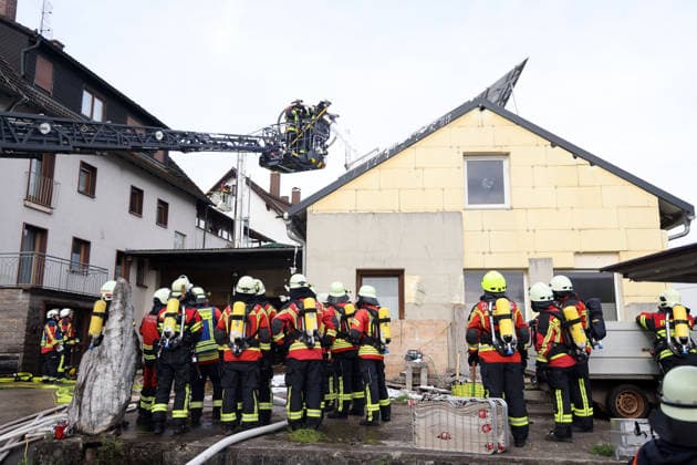 zwei Feuerwehrleute in der Drehleiter spritzen Schaum in das Gebäude wärhedn davor weitere Einsatzkräfte warten, Feuer im ehemaliges Werkstattgebäude Naturstein Stefan Wormser, Pestalozzistraße Friedhofsweg, 20.09.2026, Oberfranken, Bayern,