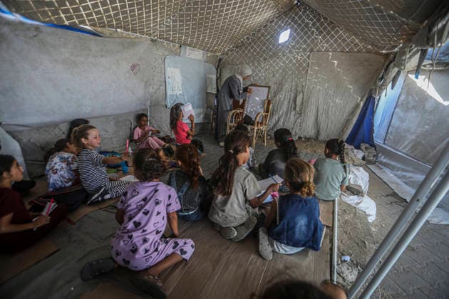 Gaza Temporary Tent Classrooms Palestinian children sit facing a teacher inside a temporary classroom tent in western Gaza City, Gaza Strip on September 20, 2026. Thousands of Palestinian children in the Gaza Strip have resumed lessons in temporary classrooms as the education system continues to face widespread disruption and damage following the war. Temporary learning spaces, including tents, are being used as schools and educational facilities remain damaged or unavailable. Gaza Gaza Strip Palestinian Territories Copyright: xFaizxQreqax