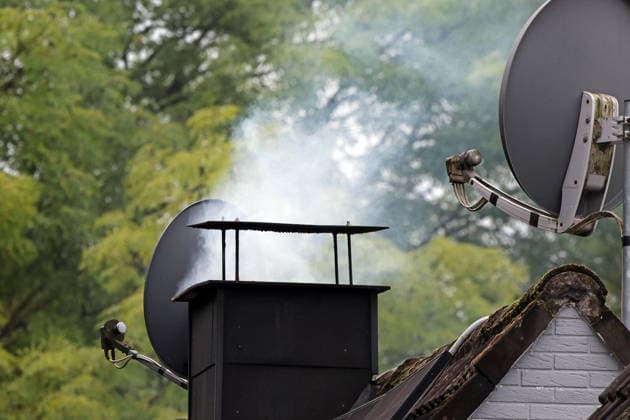 Rauch aus einem Kamin Rauchender Kamin mit sauberer Verbrennung auf einem Dach zu Beginn der Heizsaison im Herbst bei niedrigen Temperaturen.