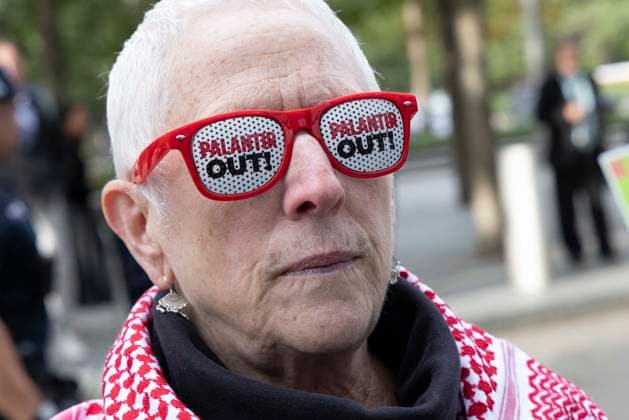 September 23, 2026, New York, New York, USA: A protester wears glasses that read PALANTIR OUT! and holds a sign that reads MT SINAI COMPLICIT DO NO HARM! DR. CARR, YOU ABANDONED TRANS YOUTH! TRANS EQUITY equals LIFE with an image of Dr. Carr. ACT UP NY leads a coalition of organizations blockading the entrance to 1 WTC and later blocking traffic on the West Side Highway demonstrating under the banner AI OUT OF OUR HEALTHCARE! PALANTIR OUT OF MOUNT SINAI! as the Newsweek AI Health Summit is held inside the building and a keynote speaker is Dr. Brendan Carr, (not pictured) CEO of Mount Sinai. Approximately 20 protesters are arrested by NYPD. Part of the MONEY FOR AIDS and HEALTHCARE! NOT FOR ICE and WARFARE! ACT UP (AIDS Coalition To Unl  - ZUMAr174 20260923_znp_r174_006 Copyright: xGinaxMxRandazzox