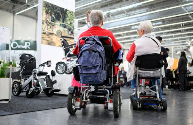 Besucher im Rollstuhl informieren sich. REHACARE Fachmesse für Rehabilitation und Pflege, vom 23.09. - 26.09.2026 in Düsseldorf Deutschland. Messe