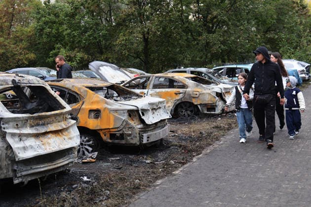 People walk past burnt-out cars at a parking lot in the Podilskyi district after an overnight Russian attack, Kyiv, Ukraine, September 24, 2026. On Thursday night, September 24, Russian forces launched a ballistic missile strike on Kyiv, followed by drone assaults on the capital and region. By morning, two people were confirmed killed and eight injured. The attack caused fires and destruction across several districts, damaging medical facilities, apartment blocks, private homes, and vehicles. The maternity hospital in the Podilskyi district sustained damage to windows, doors, and parts of the facade from the first to fifth floors, as well as to windows in the laundry and boiler rooms. Patients, children, and medical staff were unharmed, hav Copyright: xPavloxBahmutx