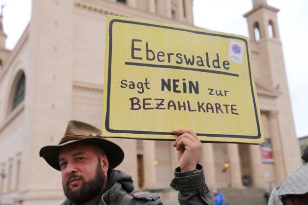 Ein Demonstrant steht mit Schild Eberswalde sagt Nein zur Bezahlkarte am Landtag während einer Demonstration gegen die Bezahlkarte für Flüchtlinge in Brandenburg, Potsdam, 25. September 2026. Demo gegen Bezahlkarte in Potsdam