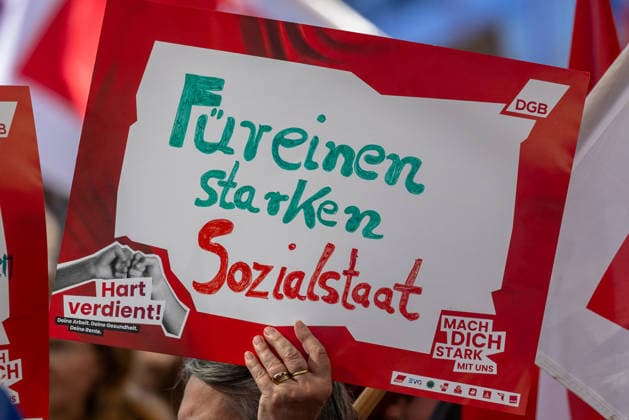 DGB Bayern - Hart verdient! Groß-Kundgebung, Nürnberg, 26.09.2026 Eine Teilnehmerin hält bei einer Kundgebung des DGB Bayern ein Schild mit der Aufschrift Für einen starken Sozialstaat in die Höhe. Ihre Geste wirkt entschlossen, im Hintergrund sind weitere Plakate mit der Aufschrift Hart verdient! zu sehen. Nürnberg Bayern Deutschland