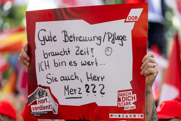 DGB Bayern - Hart verdient! Groß-Kundgebung, Nürnberg, 26.09.2026 Eine Teilnehmerin hält bei einer Kundgebung des DGB ein handbeschriftetes Plakat mit der Forderung Gute Betreuung Pflege braucht Zeit! Ich bin es wert... Sie auch, Herr Merz??? in die Höhe. Das Schild trägt zudem den Slogan Hart verdient! sowie das DGB-Logo und den Aufruf Mach dich stark mit uns . Nürnberg Bayern Deutschland