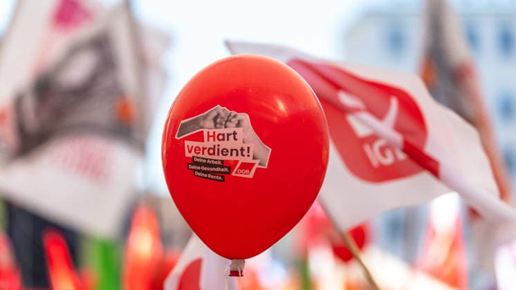 DGB Bayern - Hart verdient! Groß-Kundgebung, Nürnberg, 26.09.2026 Ein roter Luftballon mit der Aufschrift Hart verdient! Deine Arbeit. Deine Gesundheit. Deine Rente. und DGB-Logo ist zentrales Motiv einer Kundgebung. Im Hintergrund sind Fahnen der IG Metall sowie weitere Gewerkschaftsflaggen zu erkennen. Nürnberg Bayern Deutschland