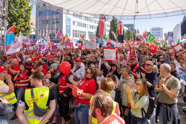 DGB Bayern - Hart verdient! Groß-Kundgebung, Nürnberg, 26.09.2026 Am Kornmarkt versammeln sich zahlreiche Teilnehmende der DGB-Kundgebung Hart verdient! mit roten Fahnen, Warnwesten und Plakaten. Mehrere Personen applaudieren und rufen mit erhobenen Händen, eine Frau hält einen roten Luftballon vor ihr Gesicht. Nürnberg Bayern Deutschland