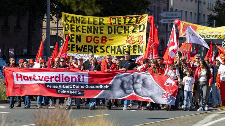 DGB Bayern - Hart verdient! Groß-Kundgebung, Nürnberg, 26.09.2026 Ein Demozug des DGB zieht am Frauentorgraben durch die Straßen, angeführt von Teilnehmern mit einem großen Transparent Hart verdient! . In der Mitte läuft Christiane Benner, Erste Vorsitzende der IG Metall, umgeben von zahlreichen Teilnehmern mit roten Fahnen und Plakaten. Nürnberg Bayern Deutschland