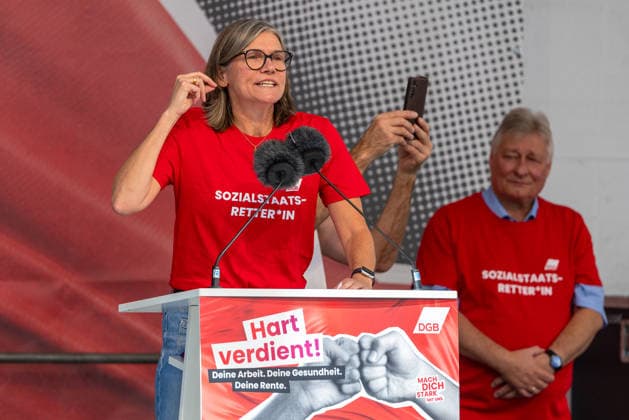 DGB Bayern - Hart verdient! Groß-Kundgebung, Nürnberg, 26.09.2026 Christiane Benner, Erste Vorsitzende der IG Metall, spricht bei einer Kundgebung des DGB am Rednerpult mit lebhafter Gestik. Sie trägt ein rotes T-Shirt mit der Aufschrift Sozialstaats-Retter*in und wirkt dabei engagiert und entschlossen. Nürnberg Bayern Deutschland