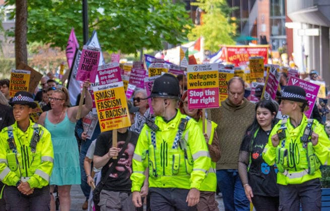 September 26, 2026, Manchester, United Kingdom: Police officers lead marchers past Number10 North during the rally. Activists in Manchester march for Stand Up To Racism against the far right. In addition to anti-racist slogans promoting diversity and migrant rights, demonstrators carried banners of the RNLI (Royal National Lifeboat Institution) following recent Patriot Platform protests. The broad coalition of trade unions, community groups, and political organisations featured prominent banners from BECTU (Broadcasting, Entertainment, Communications and Theatre Union) and Jewish Voice for Labour (JVL). Manchester, United Kingdom. Manchester United Kingdom  - ZUMAs197 20260926_aaa_s197_221 Copyright: xGaryxRobertsx