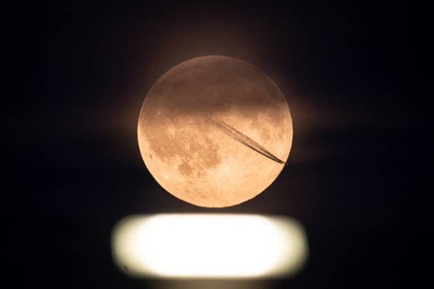 Vollmond Der Vollmond leuchtet über einem Scheinwerfer auf dem Rollfeld des Frankfurter Flughafens, während sich der Kondensstreifen eines vorbei fliegenden Flugzeuges vor dem Erdtrabant abzeichnet. Frankfurt am Main Flughafen Hessen Deutschland