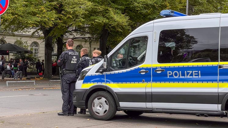 Hannover, Niedersachsen, Deutschland, Europa. Mehrere Polizeibeamte stehen neben einem Einsatzfahrzeug der Polizei und sichern den Bereich vor einer Fußballveranstaltung. Im Hintergrund befinden sich Besucher und Fans im Umfeld des Waterloo Biergartens. Symbolbild für Polizeieinsatz, Sicherheitsmaßnahmen, öffentliche Sicherheit, Fußballfans und Veranstaltungsmanagement. Copyright: xAymanxAlahmedx