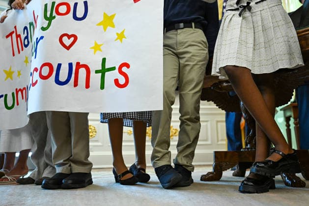 WASHINGTON, DC - OCT. 7: Kids holding a sign shift their feet as United States President Donald J Trump speaks during an announcement on Trump Accounts in the Oval Office of the White House in Washington, DC, USA, on Wednesday, October 7, 2026. Copyright: xAnnabellexGordon PoolxviaxCNPx MediaPunchx