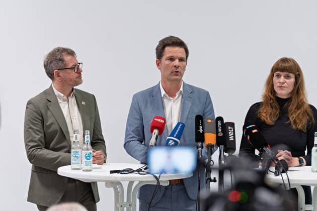 Berlin, 08.10.2026: Steffen Krach (SPD, M.) spricht neben Werner Graf (Bündnis 90 Die Grünen, l.) und Kerstin Wolter-Ehling (Die Linke, r.) beim gemeinsamen Pressestatement nach Abschluss der Vorgespräche ihrer Parteien im Foyer des Hauses der Statistik, im Vordergrund Kameras der Medien. Pressestatement von Linke, Grünen und SPD in Berlin