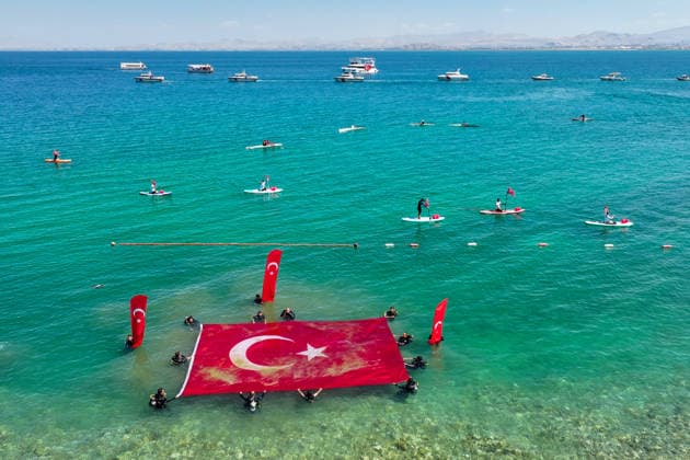 12th Van Sea Water Sports Festival kicks off on Lake Van VAN, TURKIYE - AUGUST 08: An aerial view of divers unfurling a large Turkish flag as participants and athletes taking part in the 12th Van Sea Water Sports Festival held at the Edremit-Gebze Water Sports Center on the shores of Lake Van in Van, Turkiye, on August 08, 2026. Organized to promote Lake Van and boost local tourism, the two-day event features Beach volleyball, Beachvolleyball and handball matches, flyboard demonstrations, canoeing, rowing, dragon boat races, and various recreational activities. Ozkan Bilgin Anadolu Van Turkey. Editorial use only. Please get in touch for any other usage. Copyright: x2026xAnadoluxOzkanxBilginx