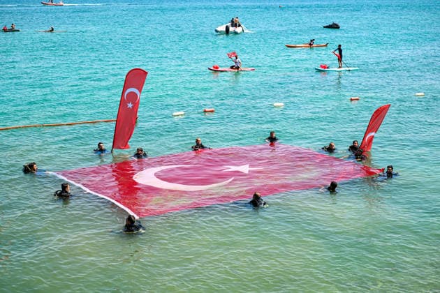 12th Van Sea Water Sports Festival kicks off on Lake Van VAN, TURKIYE - AUGUST 08: An aerial view of divers unfurling a large Turkish flag as participants and athletes taking part in the 12th Van Sea Water Sports Festival held at the Edremit-Gebze Water Sports Center on the shores of Lake Van in Van, Turkiye, on August 08, 2026. Organized to promote Lake Van and boost local tourism, the two-day event features Beach volleyball, Beachvolleyball and handball matches, flyboard demonstrations, canoeing, rowing, dragon boat races, and various recreational activities. Ozkan Bilgin Anadolu Van Turkey. Editorial use only. Please get in touch for any other usage. Copyright: x2026xAnadoluxOzkanxBilginx