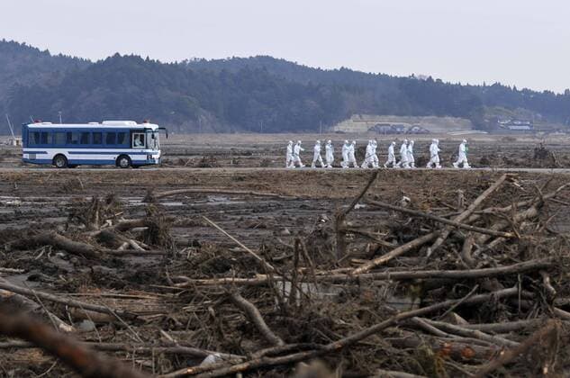 April 15, 2011, Minami - Soma, Japan - Wearing protective gear, a police search party shift through debris as they search for missing people in Minami-Soma, Fukushima Prefecture, on Friday, April 15, 2011. Southern half of the town falls within the 20km radius from the crippled Fukushima No. 1 nuclear power plant, where residents have been ordered to evacuate. More than 2,200 people have been missing in Fukushima Prefecture alone since an earthquake and tsunami hit Japan northeastern region on March 11. ( quba002239)